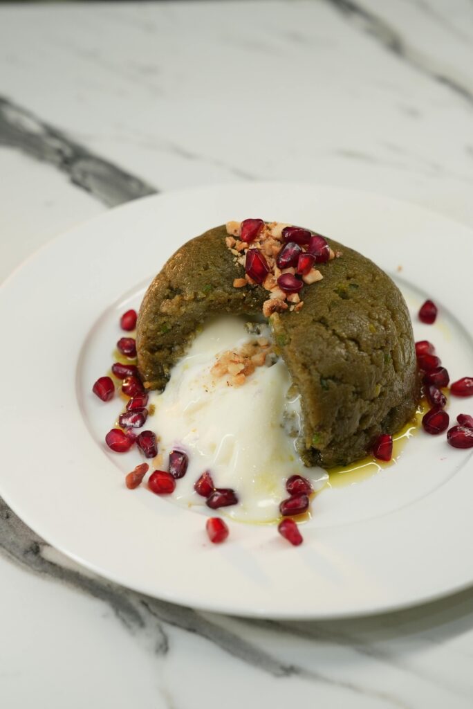 A delectable halva dessert topped with pomegranate seeds, served on a white plate for a sweet indulgence.